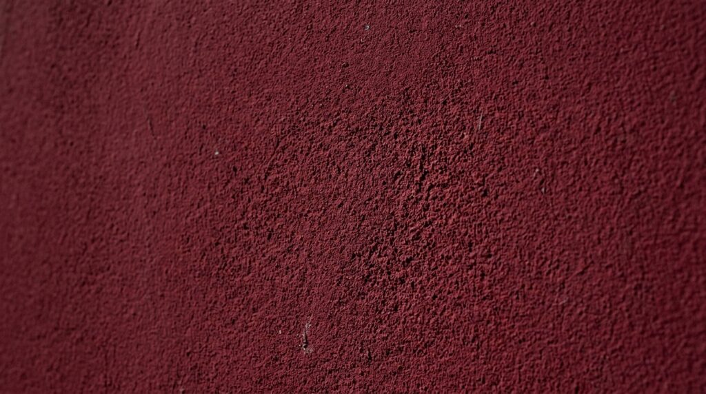 Close-up of a textured matte maroon wall paint finish for interior design and home renovation.